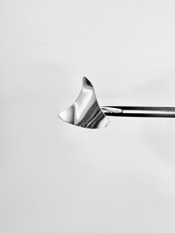 A tweezer holding a silver ring shaped as a wavy triangle.