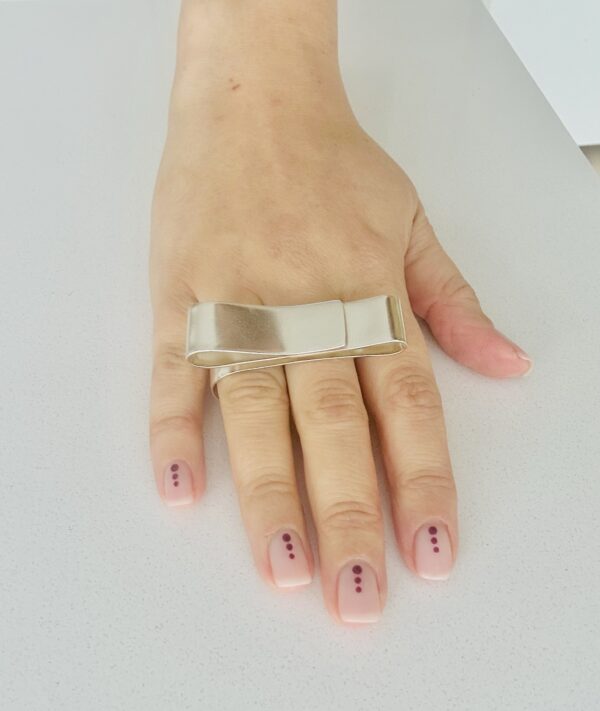 A hand wearing a handmade silver ring shaped as a big swirl.