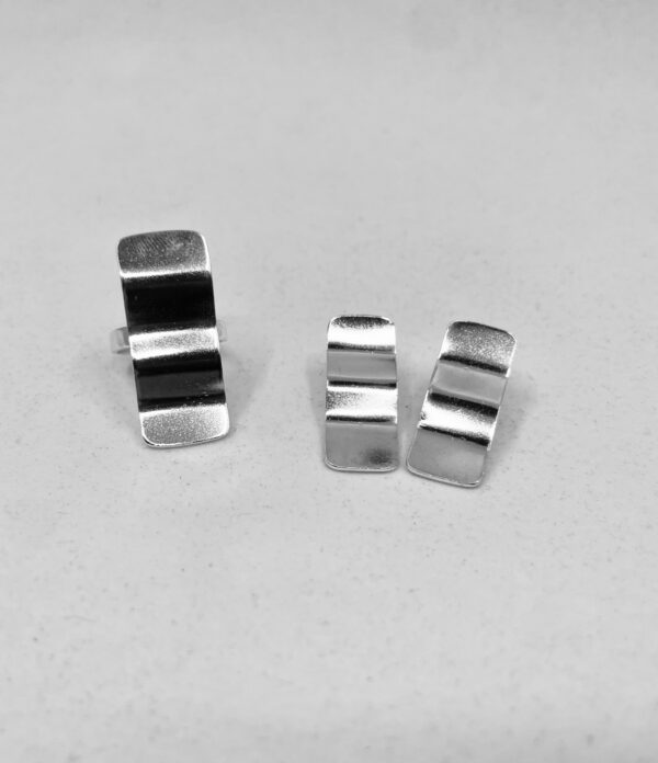 A silverring and a pair of earrings shaped as wavy rectangles.