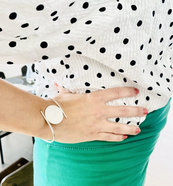 A woman waering a polka dotted shirt and green skort wearing a silver bracelet